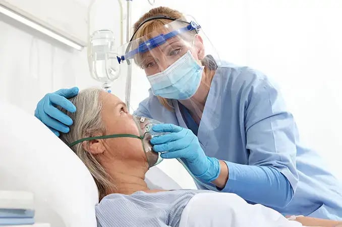 RRT nurse holding a breathing mask for a patient in hospital bed