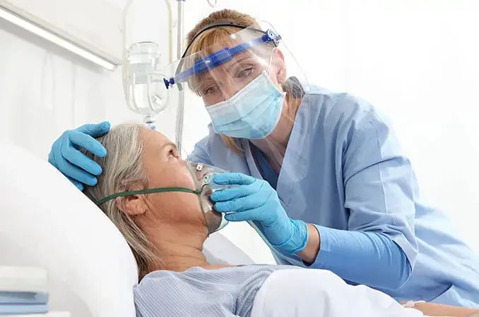 RRT nurse holding a breathing mask for a patient in hospital bed RRT nurse holding a breathing mask for a patient in hospital bed
