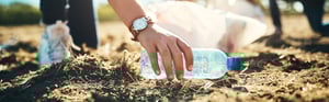 young person picking up trash in a park